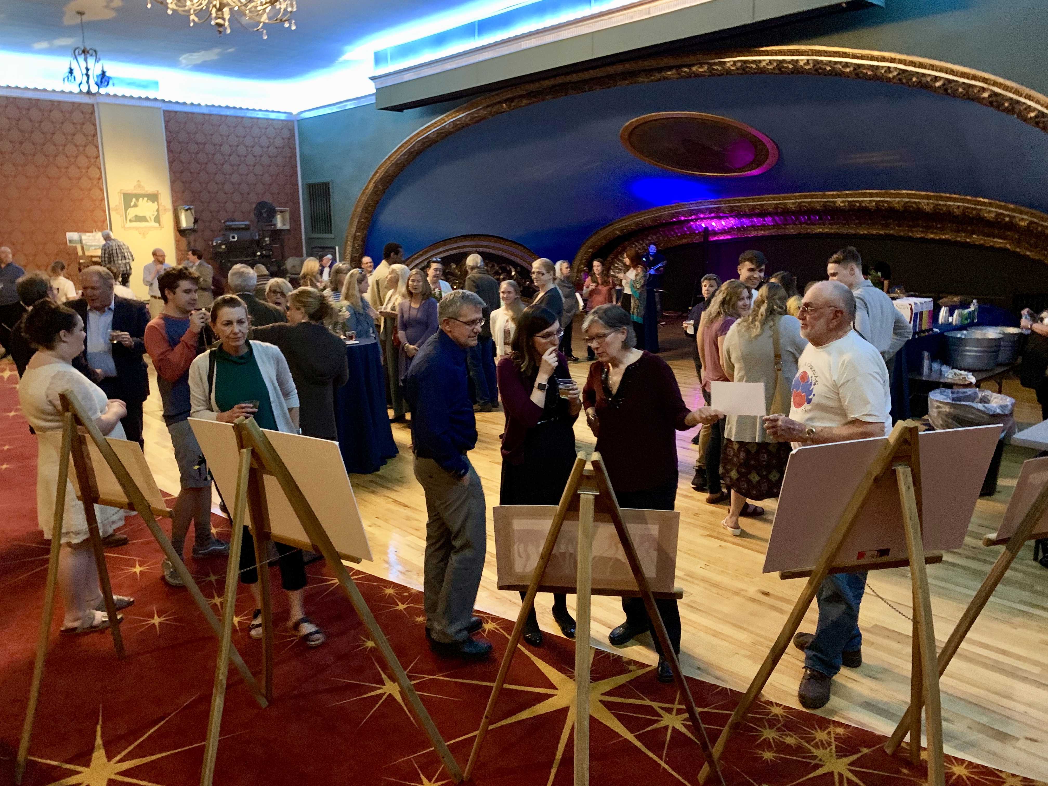 people stand in front of easels with canvas on them and around a large room with curved blue ceiling
