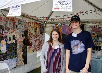 Two Emerging Young Artists smile in a booth showing their artwork