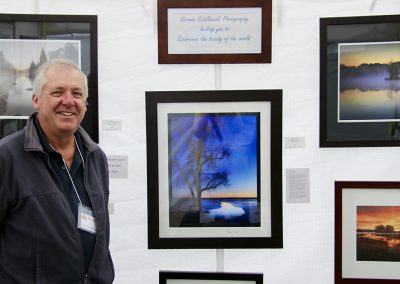 An artist smiles with prints of his photography at the Colorscape Chenango Arts Festival